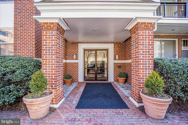 doorway to property with a balcony, french doors, and brick siding