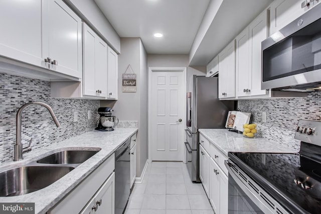 kitchen with light stone countertops, appliances with stainless steel finishes, sink, and white cabinets