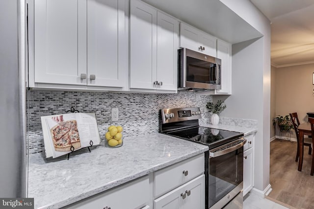 kitchen featuring tasteful backsplash, light stone countertops, appliances with stainless steel finishes, and white cabinets