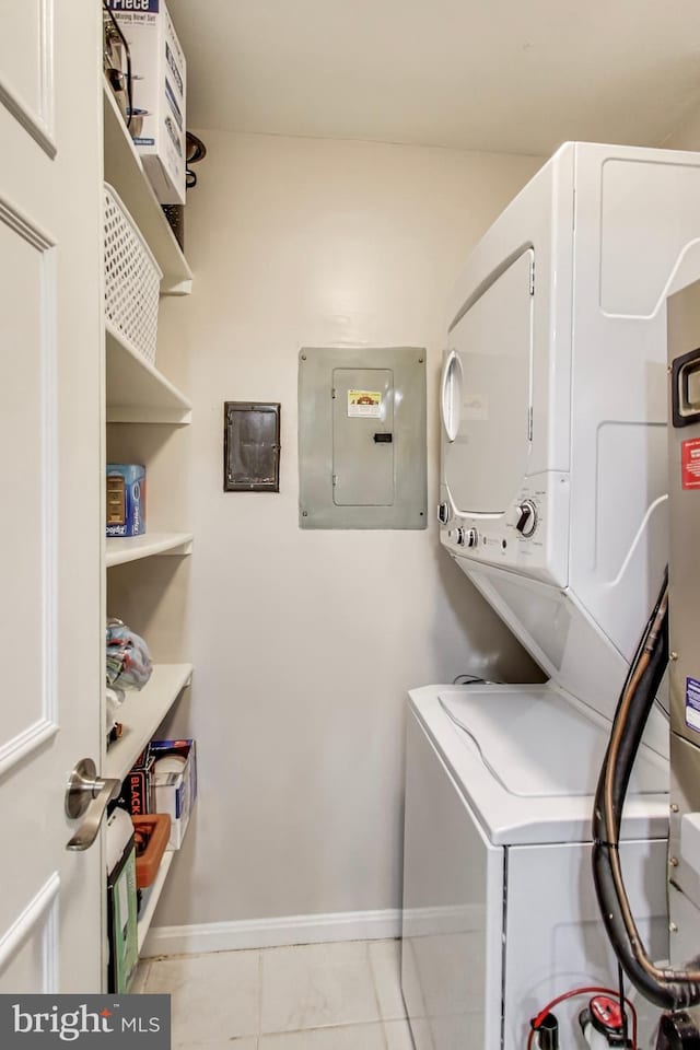 laundry area featuring stacked washer and dryer, light tile patterned floors, and electric panel