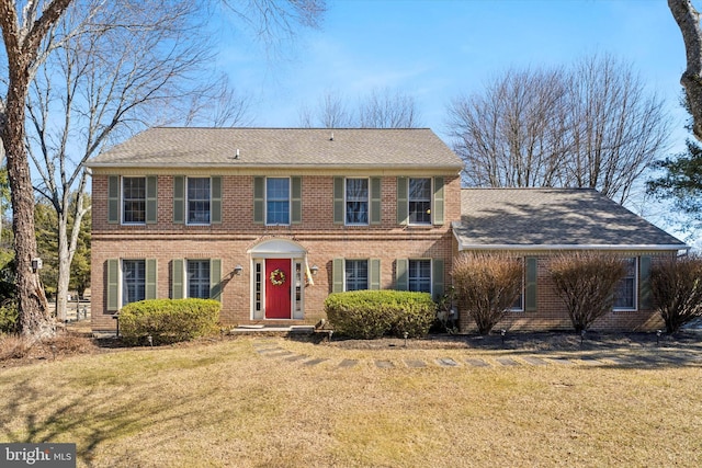 colonial inspired home featuring brick siding and a front lawn