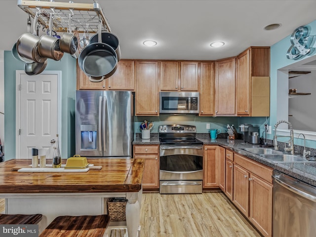 kitchen with stainless steel appliances, brown cabinets, a sink, and light wood finished floors