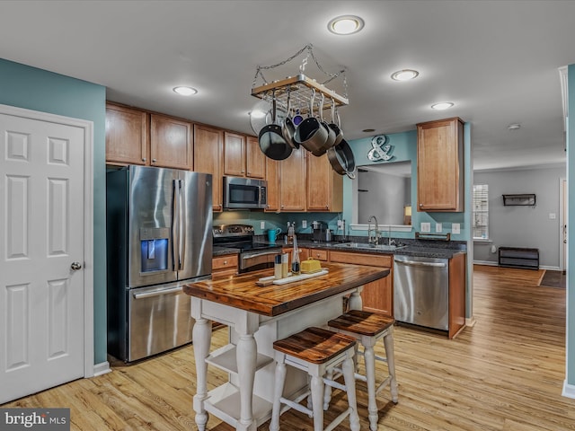 kitchen featuring dark countertops, light wood finished floors, stainless steel appliances, and a sink