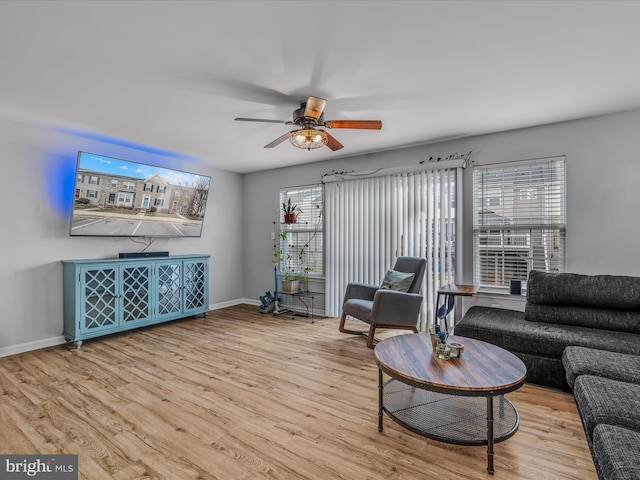 living area featuring light wood-type flooring, a ceiling fan, and baseboards