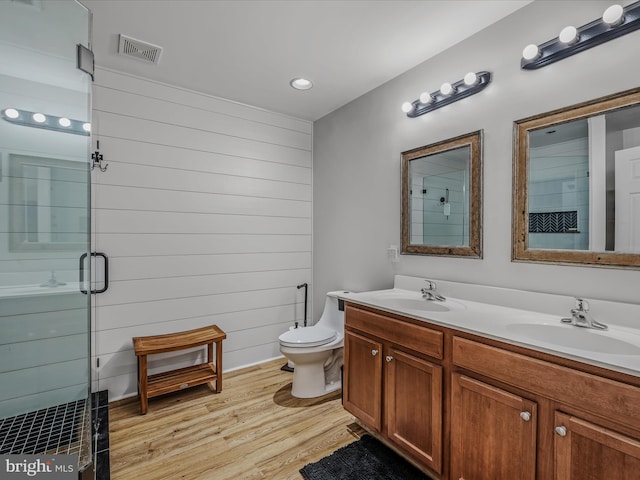 full bathroom featuring a stall shower, visible vents, a sink, and wood finished floors