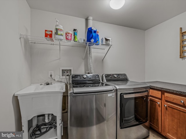 washroom with cabinet space, a sink, and separate washer and dryer