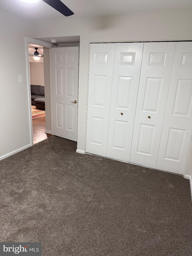 unfurnished bedroom featuring dark colored carpet and a closet