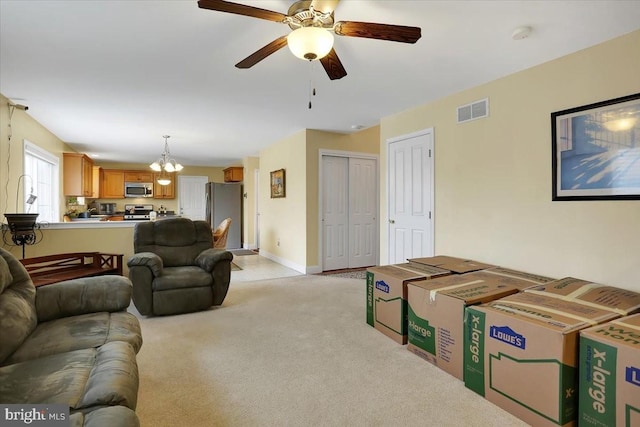 carpeted living room featuring ceiling fan with notable chandelier