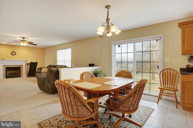 dining room with light tile patterned flooring and ceiling fan with notable chandelier