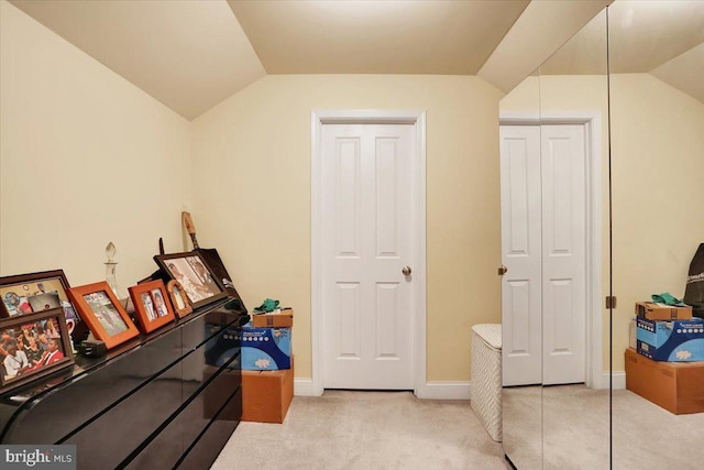 interior space featuring light colored carpet, lofted ceiling, and a closet