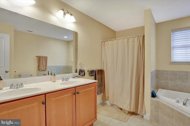 bathroom with tile patterned flooring, vanity, tiled bath, and toilet