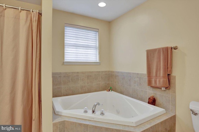 bathroom featuring toilet and tiled bath