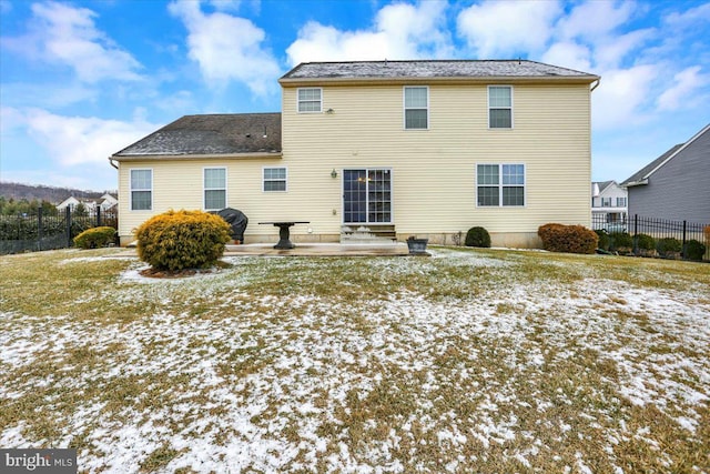 snow covered house featuring a patio and a yard