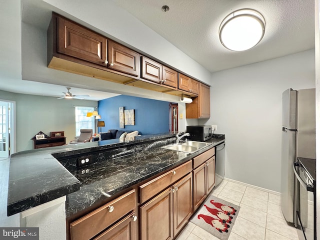 kitchen with appliances with stainless steel finishes, kitchen peninsula, sink, and light tile patterned floors