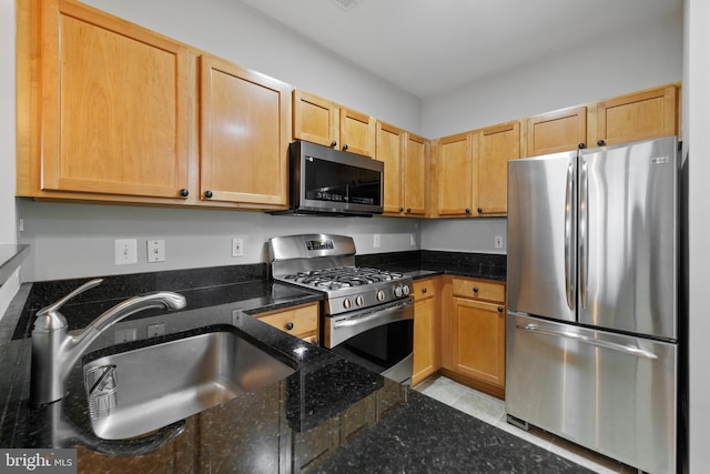 kitchen featuring sink, stainless steel appliances, and dark stone counters