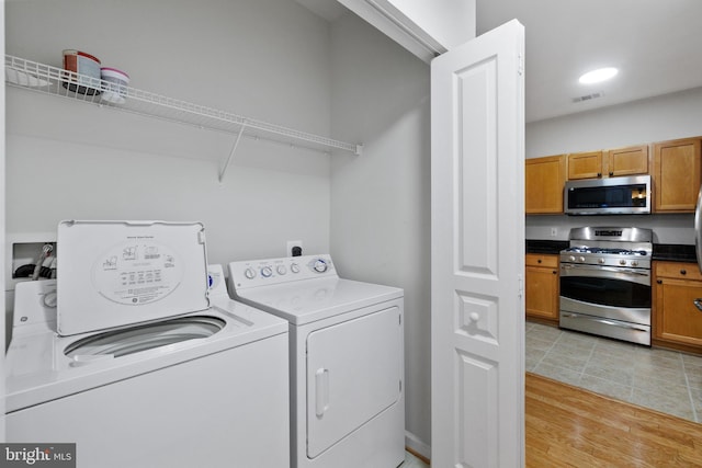 clothes washing area featuring light hardwood / wood-style floors and washer and dryer