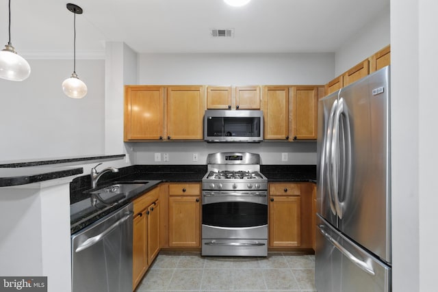 kitchen featuring appliances with stainless steel finishes, sink, dark stone counters, and decorative light fixtures