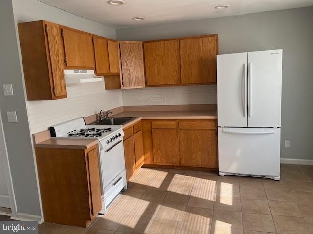 kitchen featuring sink, white appliances, decorative backsplash, and light tile patterned flooring