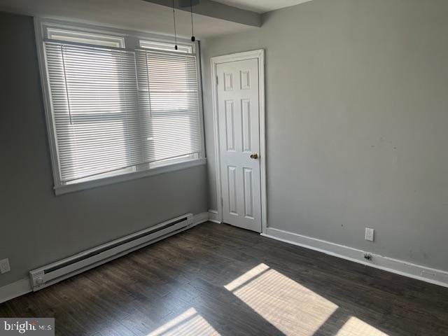 empty room with dark wood-type flooring and a baseboard radiator