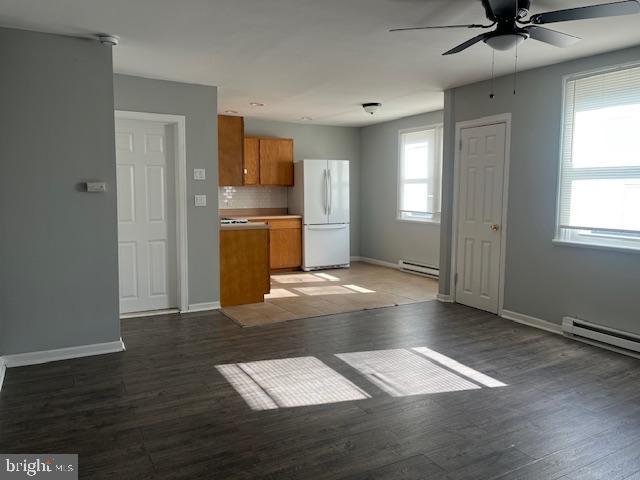 kitchen with hardwood / wood-style flooring, white fridge, baseboard heating, and decorative backsplash