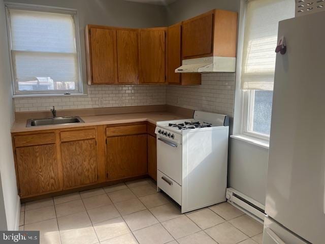 kitchen featuring sink, white range with gas stovetop, refrigerator, a baseboard heating unit, and decorative backsplash