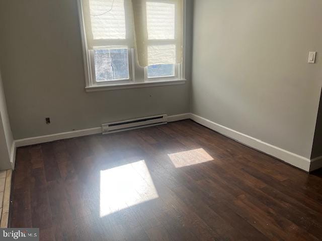 empty room featuring a baseboard heating unit and dark hardwood / wood-style floors