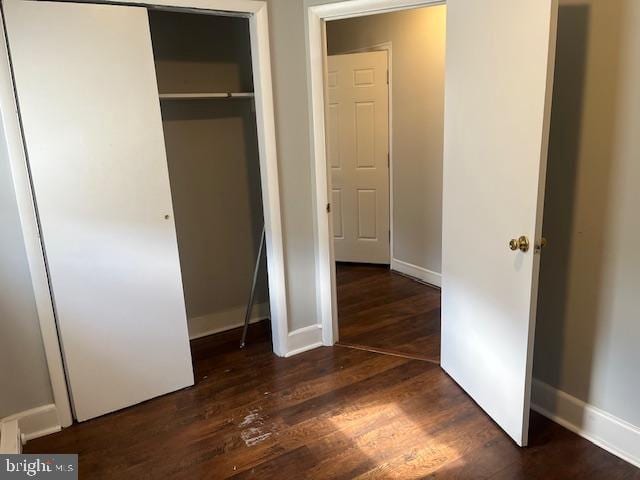 unfurnished bedroom with dark hardwood / wood-style flooring and a closet