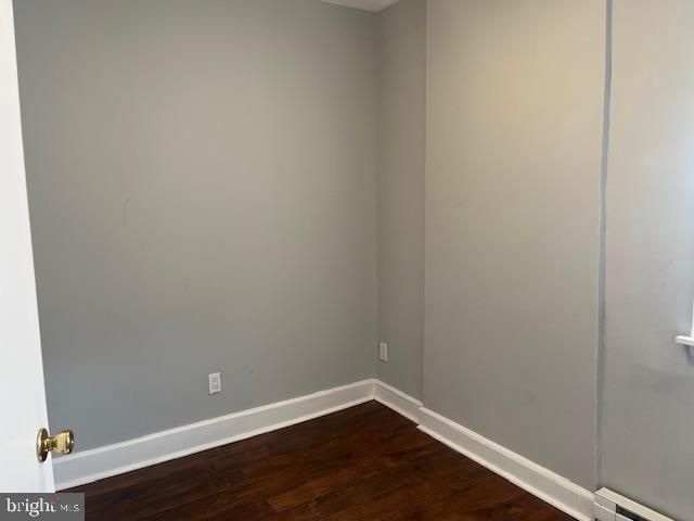 empty room with a baseboard radiator and dark wood-type flooring