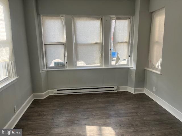 unfurnished room featuring a baseboard radiator and dark hardwood / wood-style floors