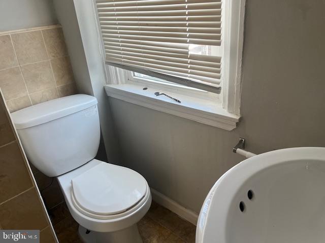 bathroom featuring tile walls and toilet