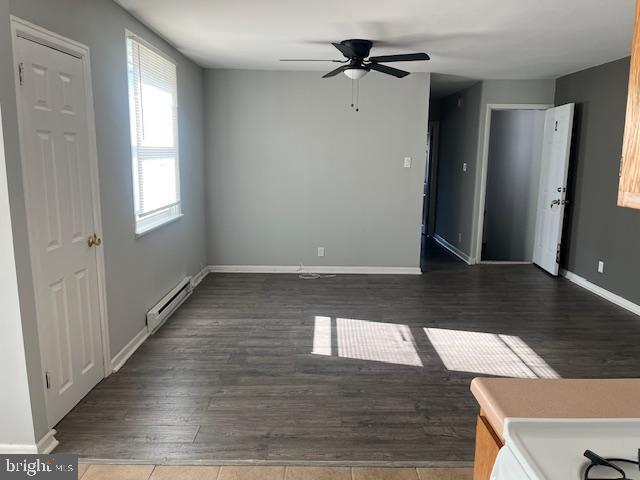 unfurnished room featuring dark hardwood / wood-style flooring, ceiling fan, and baseboard heating