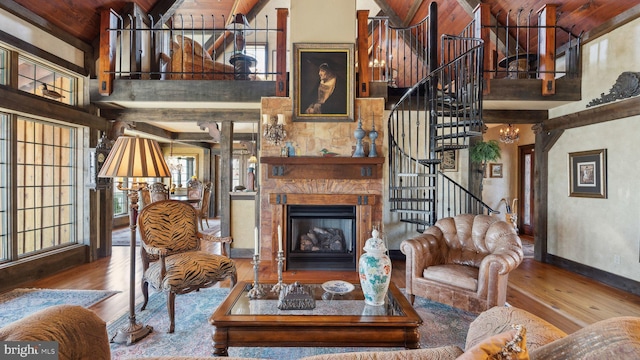 living area featuring a high ceiling, a fireplace, a notable chandelier, and wood finished floors