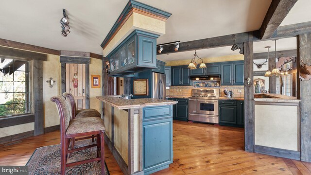 kitchen featuring stainless steel appliances, blue cabinetry, a peninsula, and light countertops