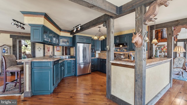 kitchen featuring light countertops, blue cabinetry, a peninsula, and freestanding refrigerator