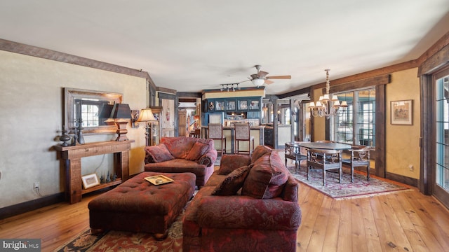 living area featuring light wood-style floors, baseboards, and ceiling fan with notable chandelier