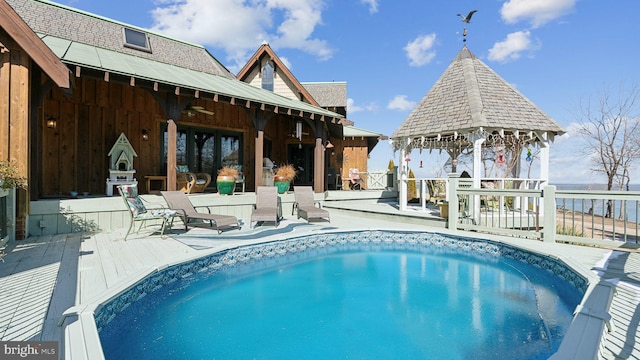 outdoor pool featuring a deck with water view and a gazebo