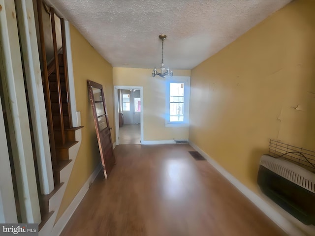 unfurnished dining area featuring hardwood / wood-style flooring, an inviting chandelier, and a textured ceiling