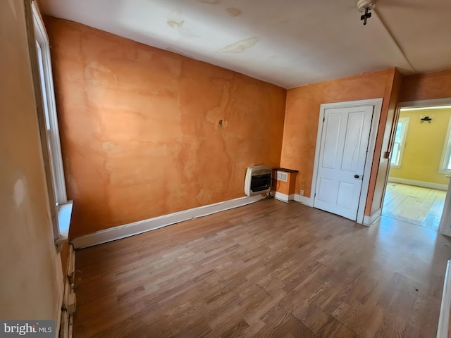 unfurnished room with hardwood / wood-style flooring and heating unit