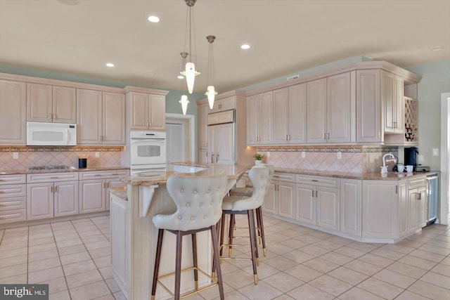 kitchen featuring pendant lighting, white appliances, a center island, light stone countertops, and light tile patterned flooring