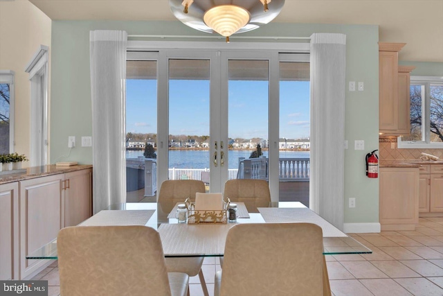 dining area featuring light tile patterned flooring and a water view