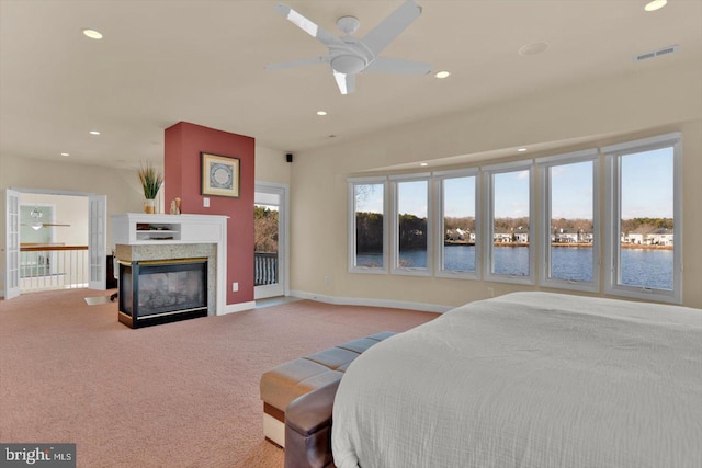 carpeted bedroom with a multi sided fireplace, a water view, and ceiling fan