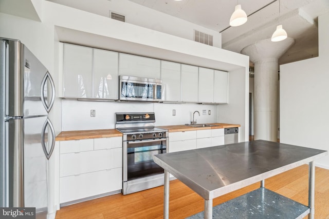 kitchen with white cabinetry, appliances with stainless steel finishes, and decorative light fixtures