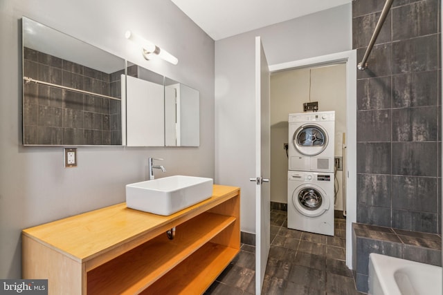 bathroom featuring vanity, stacked washing maching and dryer, and bathing tub / shower combination