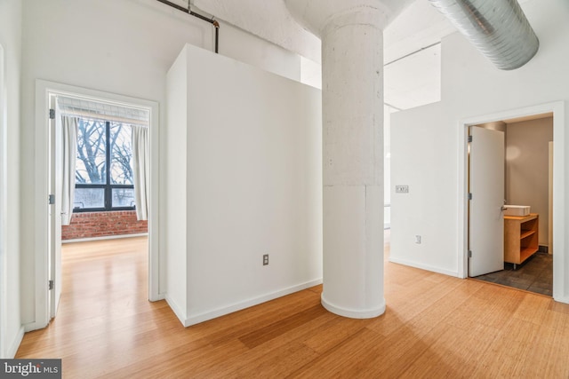 unfurnished room featuring brick wall, hardwood / wood-style floors, and a high ceiling