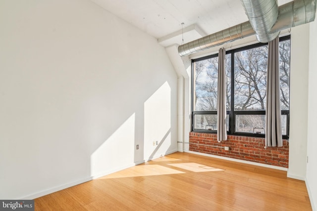 empty room featuring light hardwood / wood-style flooring and brick wall