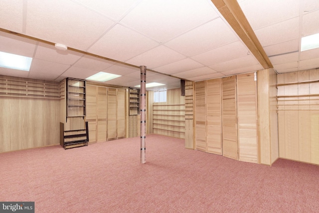 basement featuring wood walls, carpet floors, and a drop ceiling