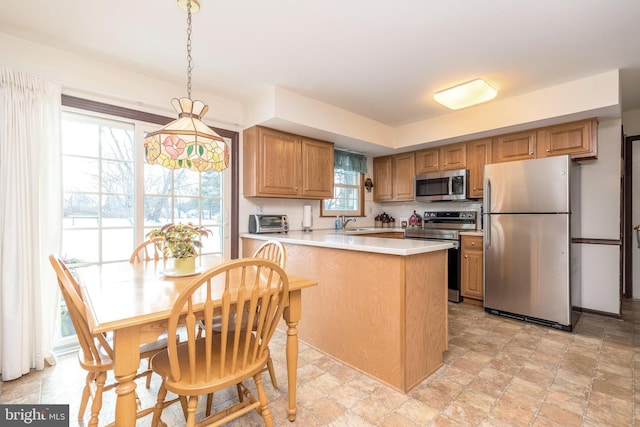 kitchen featuring appliances with stainless steel finishes, decorative light fixtures, sink, decorative backsplash, and kitchen peninsula