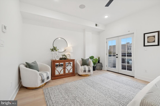 sitting room featuring light wood-type flooring, french doors, and ceiling fan