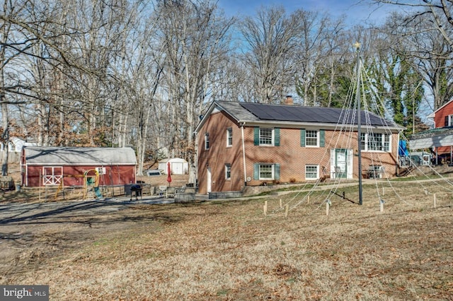 rear view of property featuring a lawn and solar panels