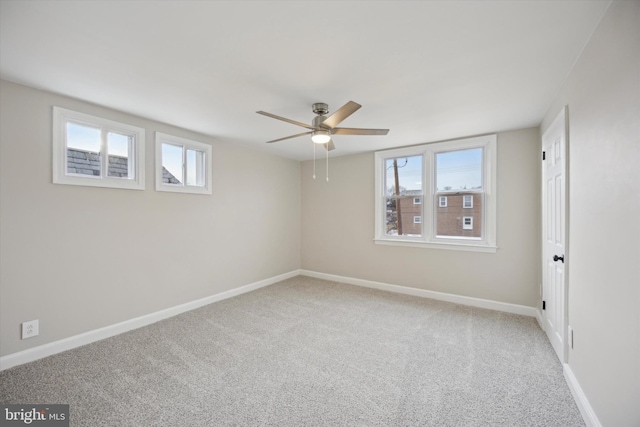 carpeted spare room featuring plenty of natural light and ceiling fan